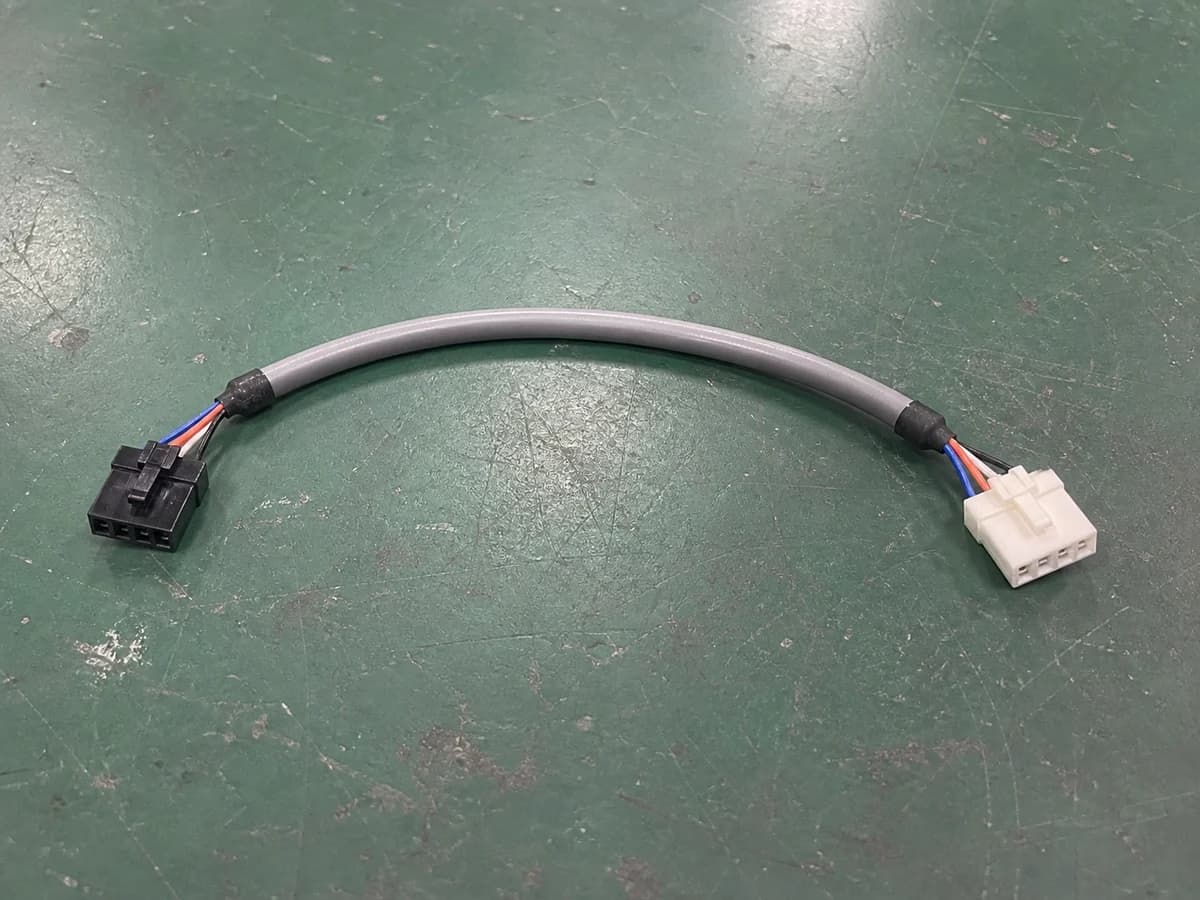 simple four-position cable assembly with rectangular connectors on a green factory workbench