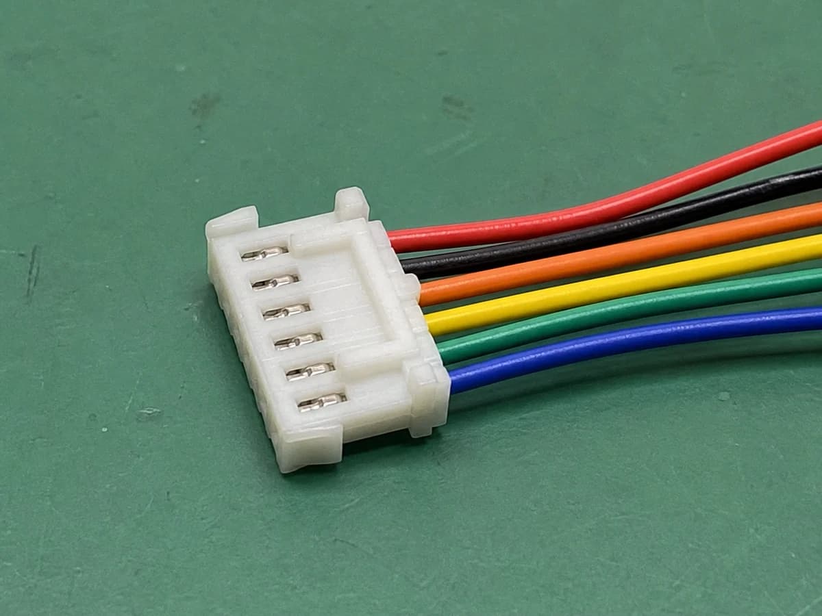 six-cavity GH-format housing with six wires on a green factory workbench